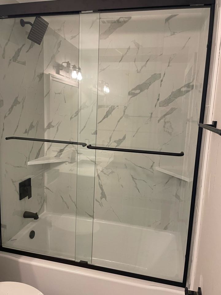 Tub and shower with sliding glass door and marble-look surround
