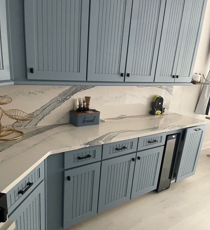 Blue beadboard cabinets with slab backsplash and counters