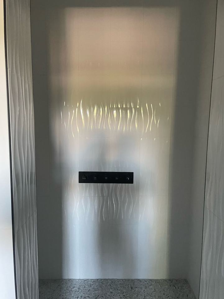 Wave tile shower wall with black control panel